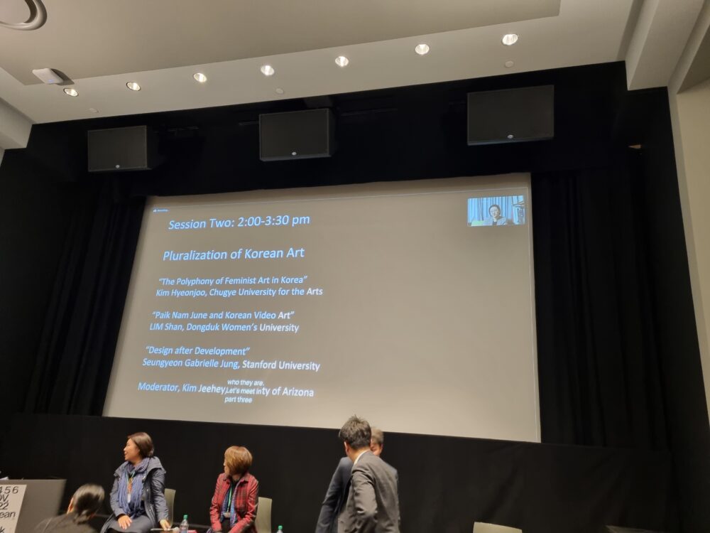 In the second session in the Gilman Auditorium, Hood Museum of Art, three individuals stand in front of a screen on which displays text on the pluralization of Korean Art.