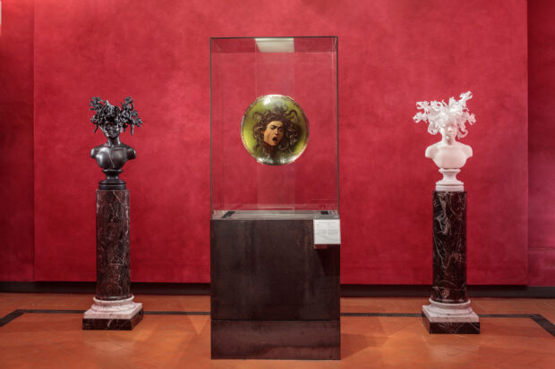 A traditional painting by Caravaggio of Medusa is flanked by two sculptures, one bronze and one white marble, of women with reptilian creatures for hair created by the artist.
