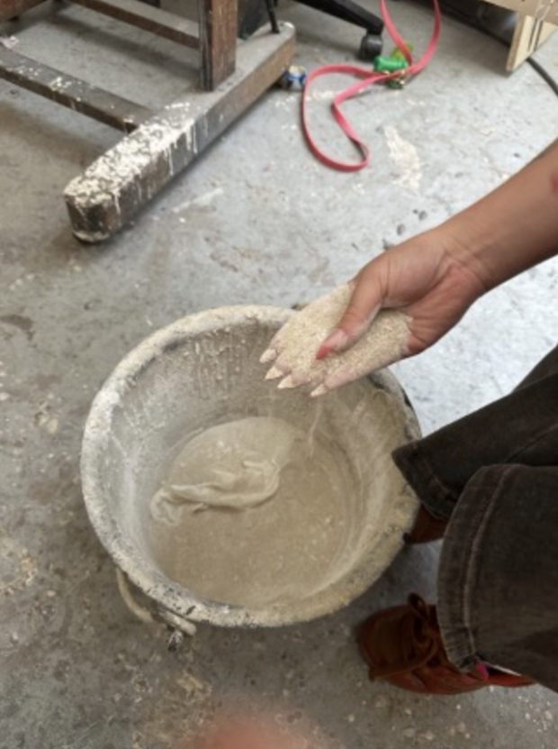 Artist's hand mixing sand